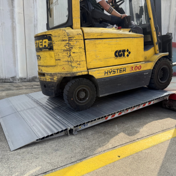 Ein Gabelstapler fährt auf die klappbare Schwerlast Containerrampe 