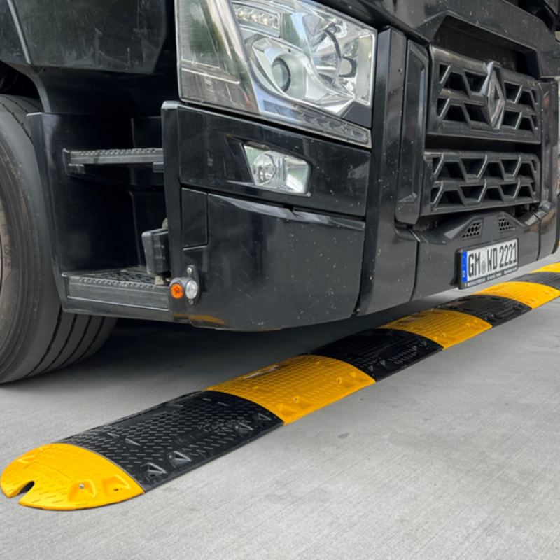EIne lange 50 mm hohe Fahrbahnschwelle ist auf einen Zementboden montiert und ein LKW fährt drüber