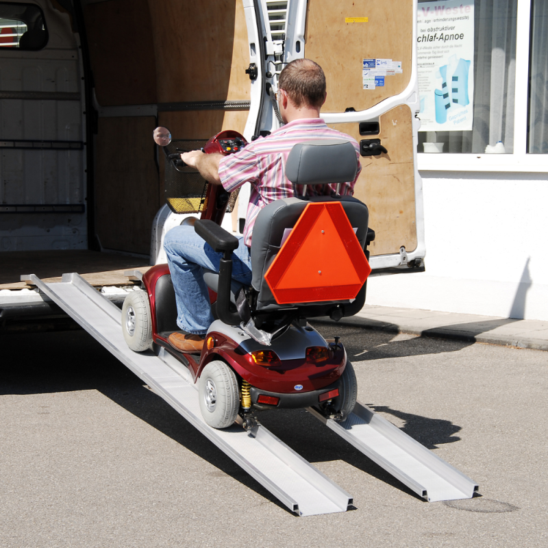Altec ABS Schienenrampen an einen Transporter gelehnt und ein elektrischer Rollstuhl fährt hoch