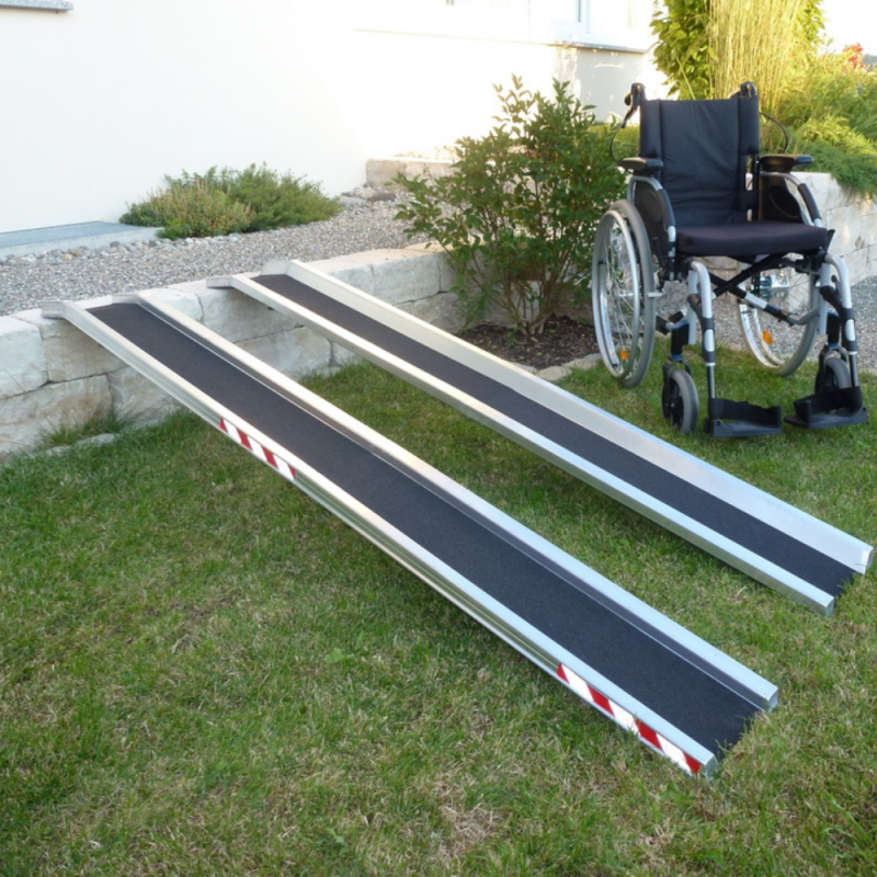 Ein Paar Leichte Alu Schienenrampen für Rollstühle an eine Kante gelehnt