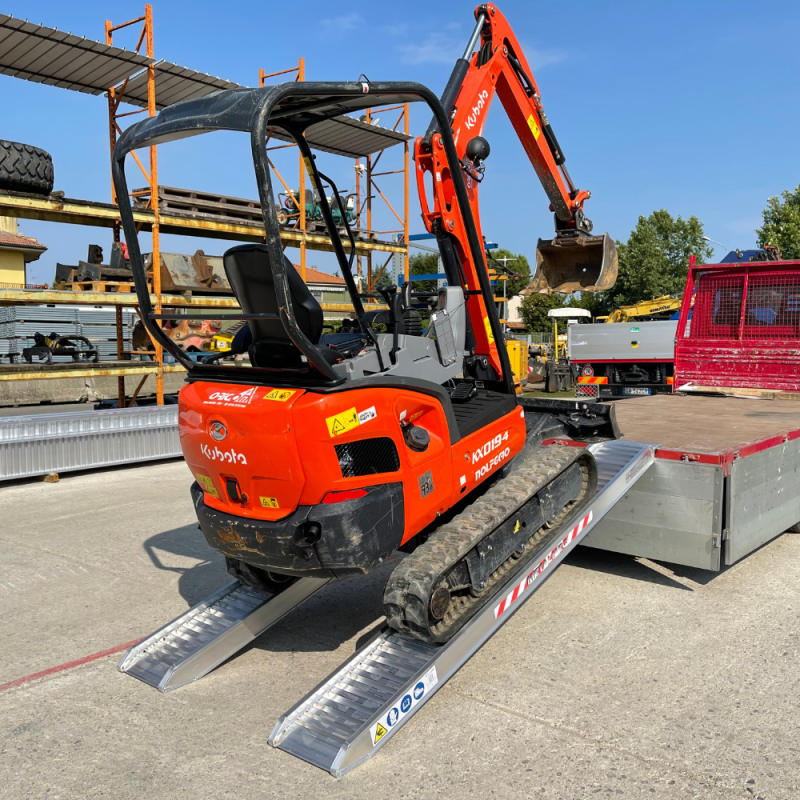 Die Alu Laderampen liegen an einer offenen Ladefläche eines Transporters an und es wird ein Mini Bagger darauf verladen